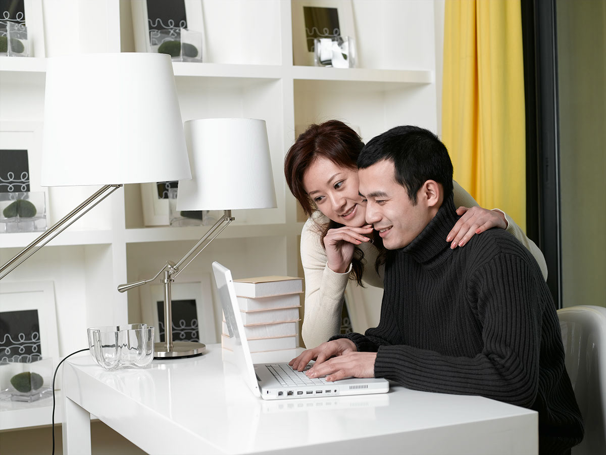 Happy Couple at Home  share a events on computer.