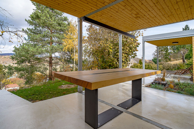 Solid wood outdoor table made from ash with steel base, placed in a natural setting