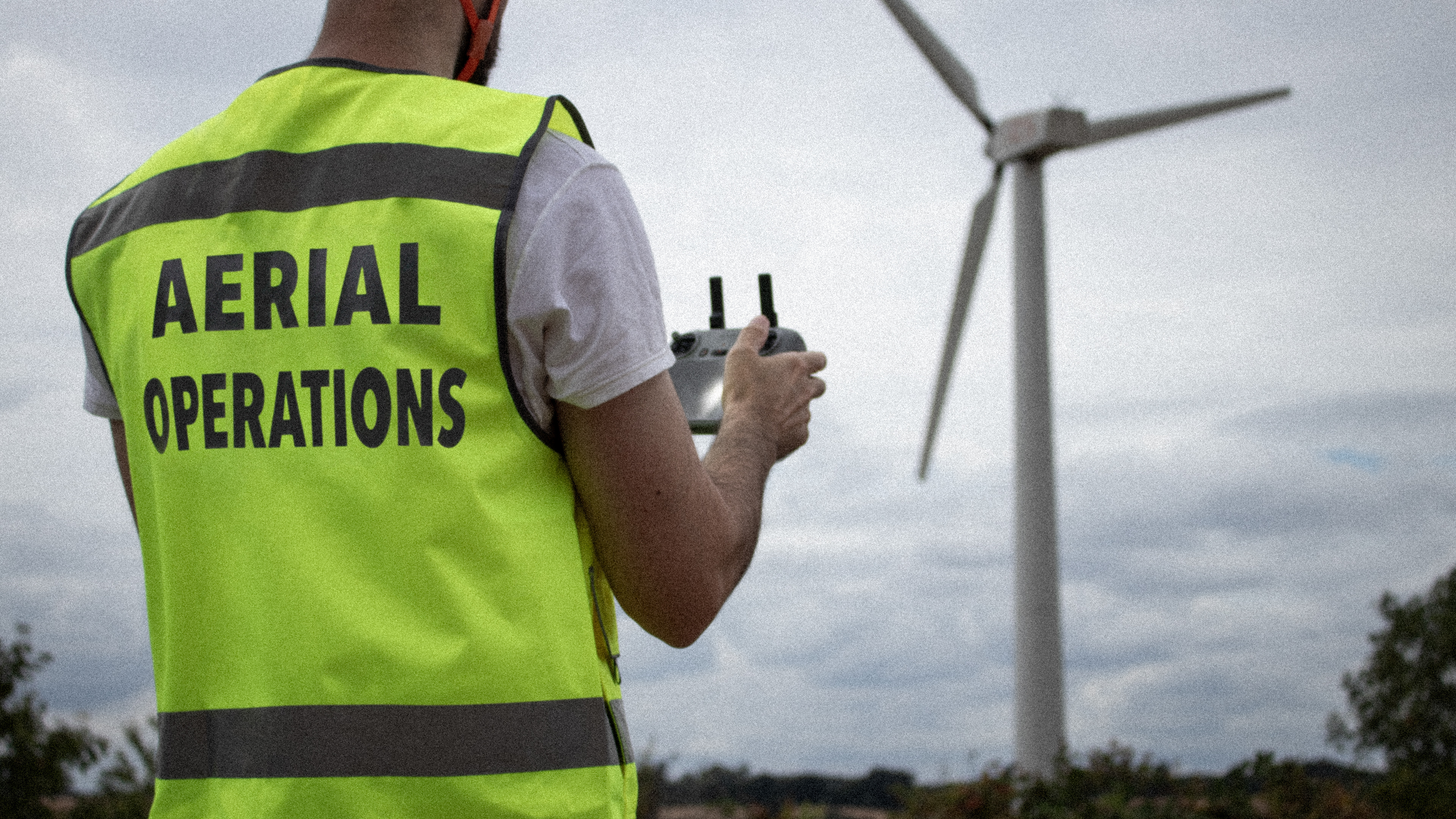 Higher Aspect Media drone operator in hi-vis vest and helmet conducting a CAA-compliant aerial filming operation in Hertfordshire.