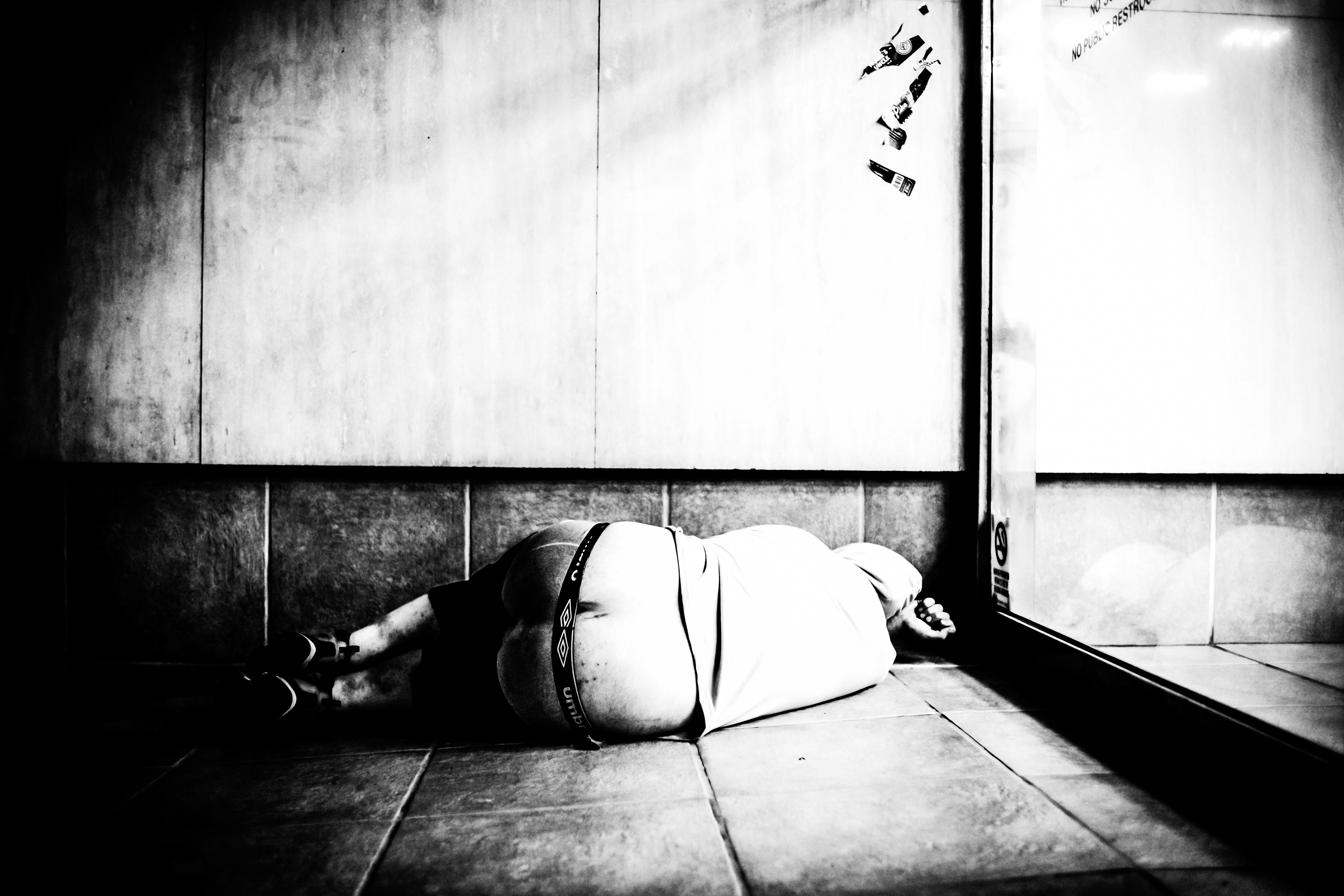 A man lies with his pants exposing his rear, laid down near the residential's entrance in downtown Seattle