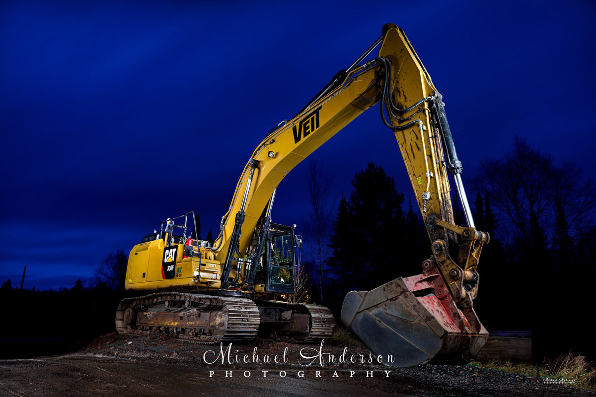 A cool light painted photograph of a Caterpillar 336F Excavator created near Split Rock Lighthouse State Park on Lake Superior.