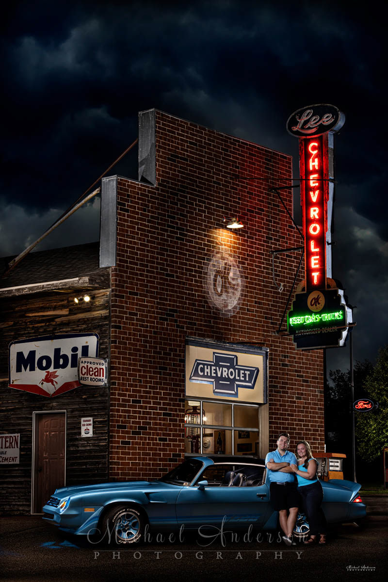 A light painted engagement photograph of a cute couple and their1980 Camaro Z28, at the vintage Chevrolet dealership on display at Little Log House Pioneer Village in Hastings, MN.