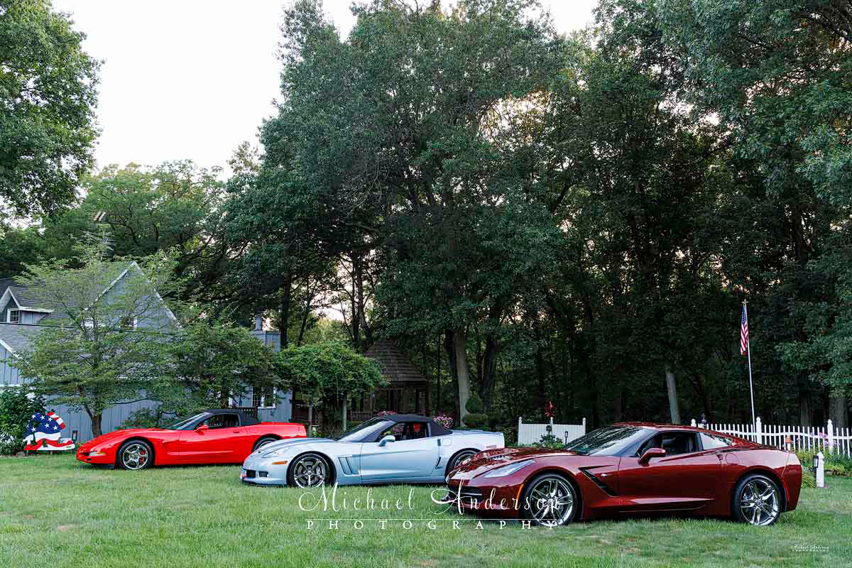 The setup photo of three Corvettes prior to light painting them in the owner's yard. A Torch Red C5 2002 Corvette Convertible, a 2012 Carlisle Blue Corvette Grand Sport Convertible, and a Long Beach Red 2019 Corvette Stingray Coupe.