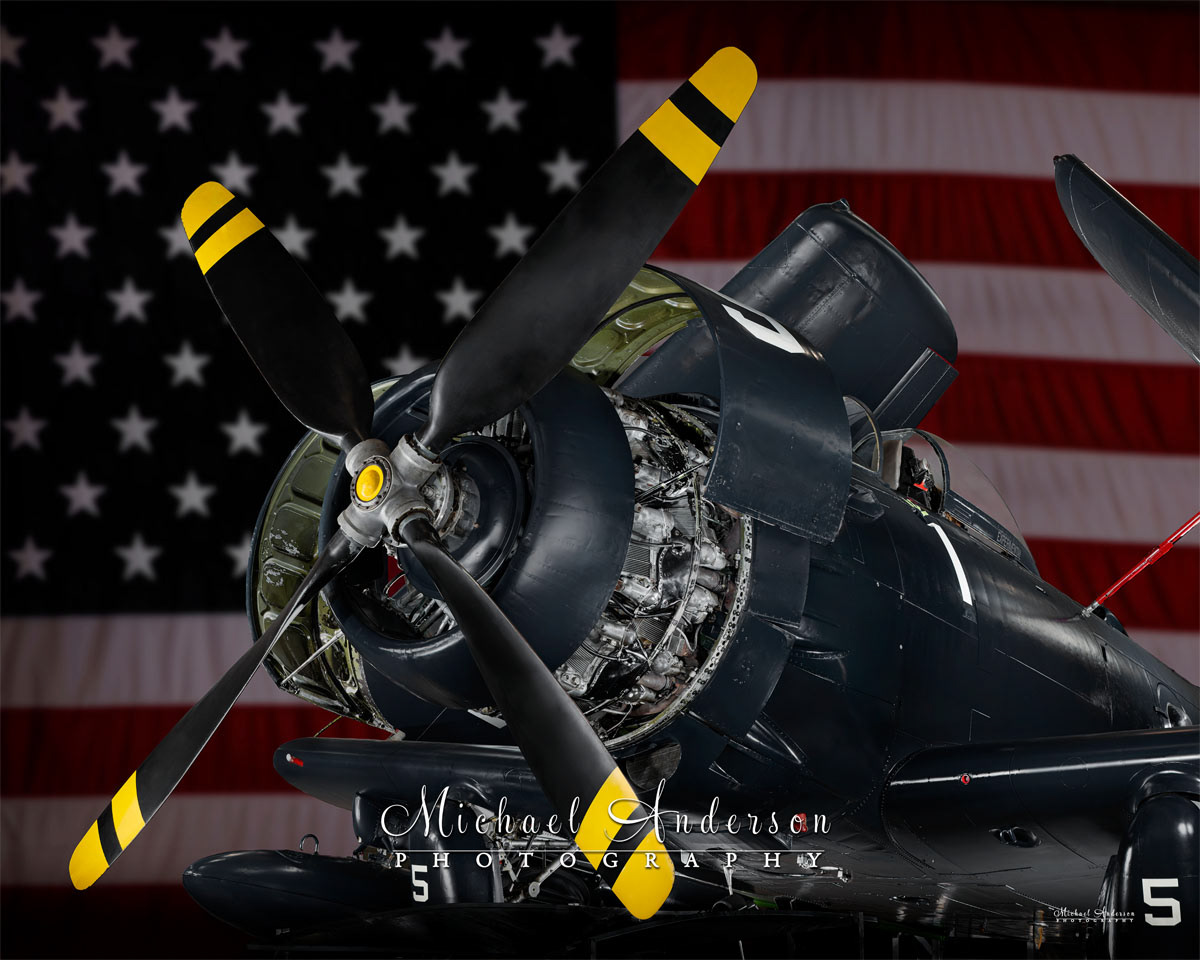 A cool light painted photograph of a 1952 AD-4N Skyraider with the American Flag as a backdrop.