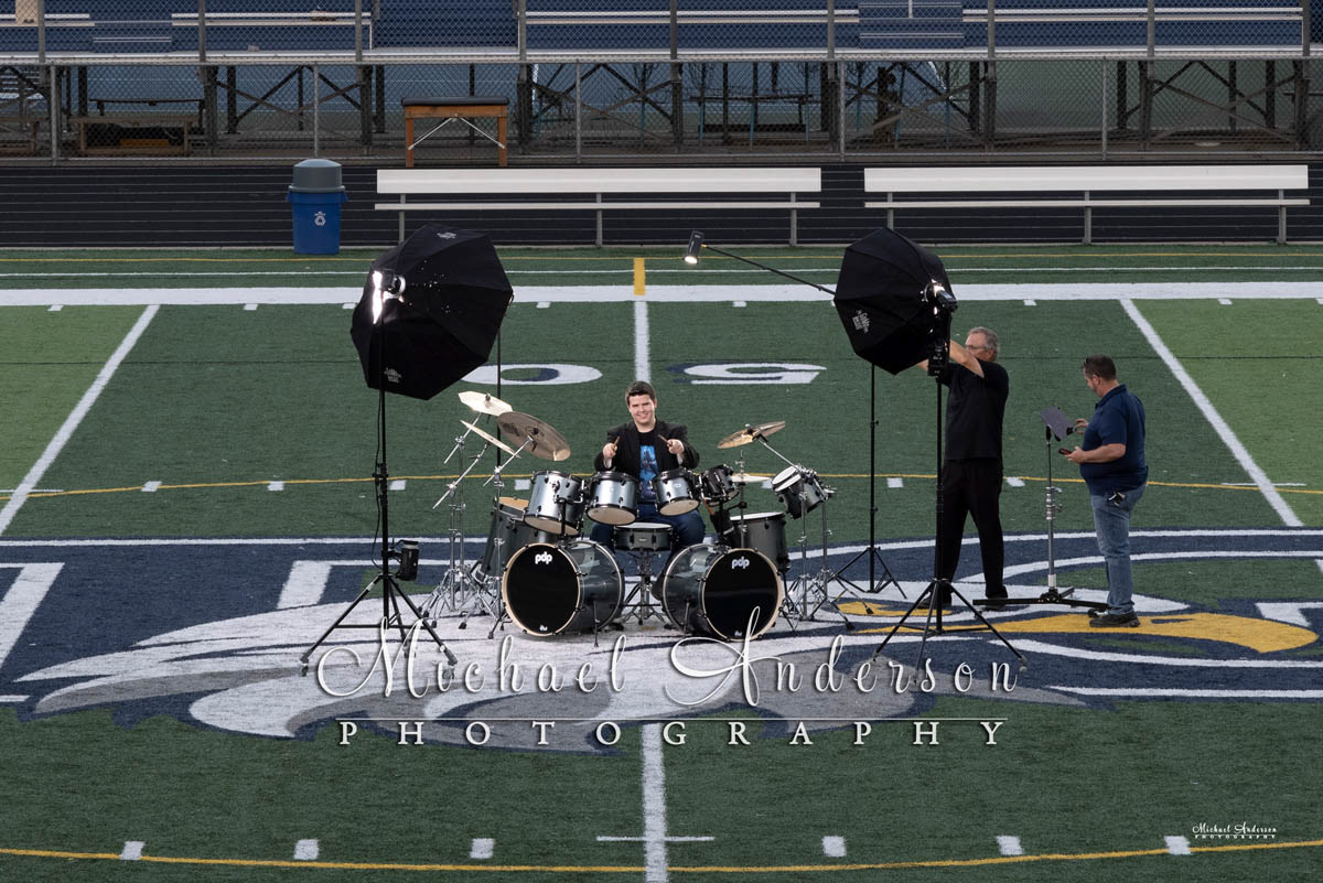Nate, his dad, and the photogrpaher, on the 50-yard line at Totino-Grace High School about to create his senior portrait light painting with his drums.