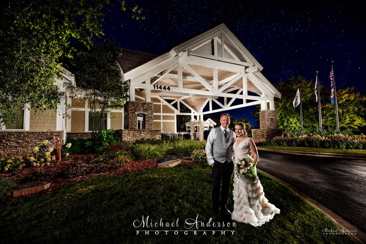 A pretty light painted wedding photo of the bride and groom outside of the clubhouse at the TPC Twin Cities in Blaine, MN.