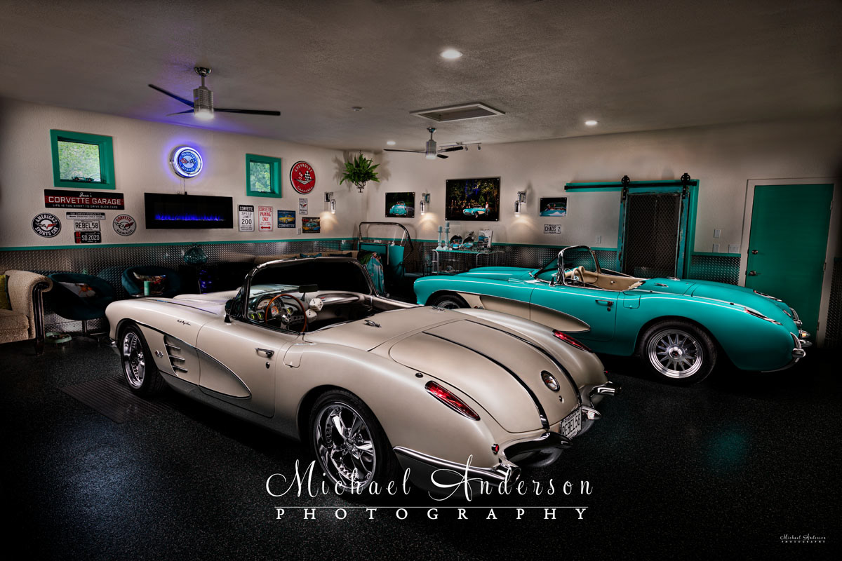 A beautiful light painted photo of two C1 Corvette Convertibles, a '57 and a '58, in a cool matching "She Shed".