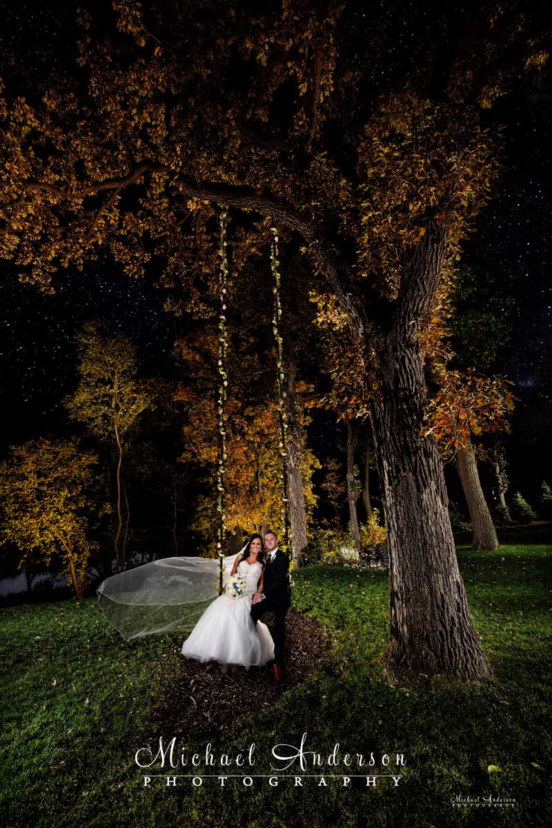 A really pretty light painted wedding photograph of the bride and groom on a swing, in the fall colors, at Leopold’s Mississippi Gardens in Minneapolis, MN.