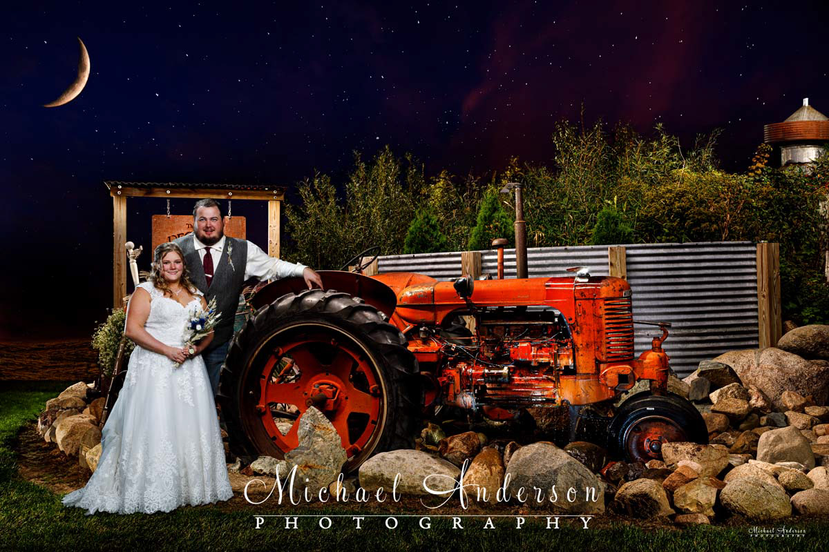 A cool light painted wedding photo of the bride and groom with a farm tractor at their wedding reception at Deglman Farm in Princeton, Minnesota.