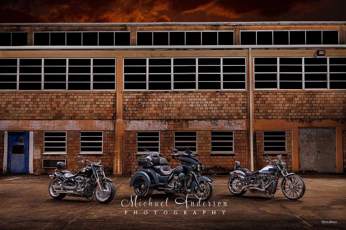 A cool light painted photograph of three Harley's. From left to right, we have a 2023 Harley-Davidson “Fat Boy”, a 2025 Harley-Davidson Tri-Glide Ultra, and a 2023 Harley-Davidson Breakout.