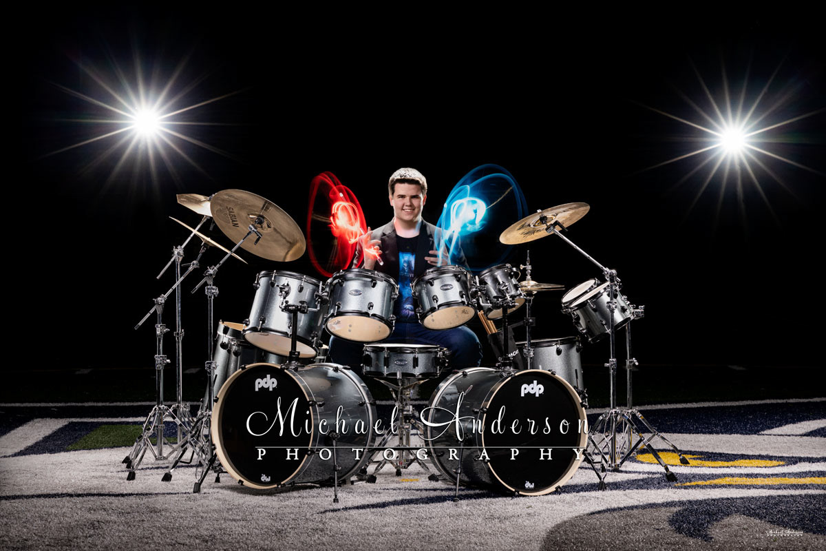 A cool light painted senior portrait of a boy and his drum set (with light-up drumsticks) on the football field at Totino-Grace High School in Fridley, MN.
