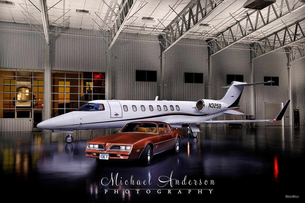 A cool one-of-a-kind light painted photograph of a 1978 Pontiac Firebird and the Learjet 45XR in the plane's hangar.