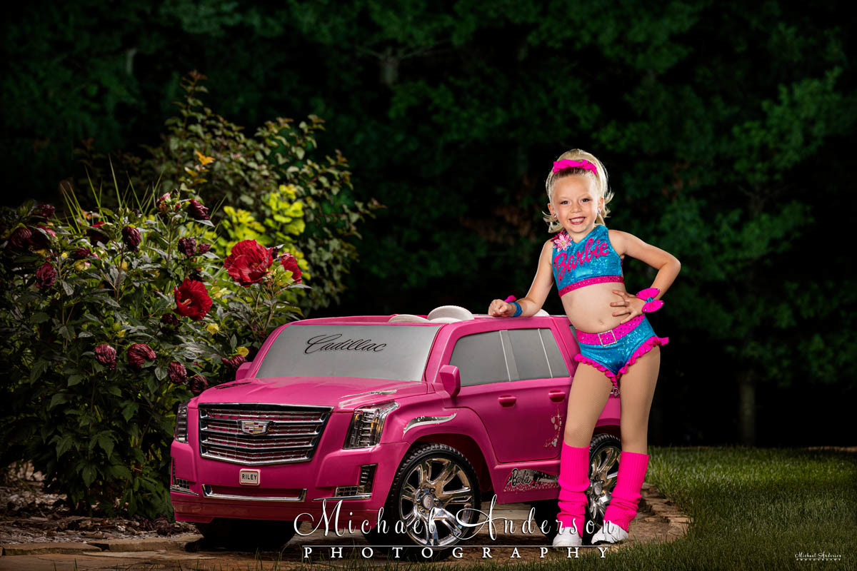 An adorable light painted kid's portrait of a little girl and her Pink Barbie Cadillac.