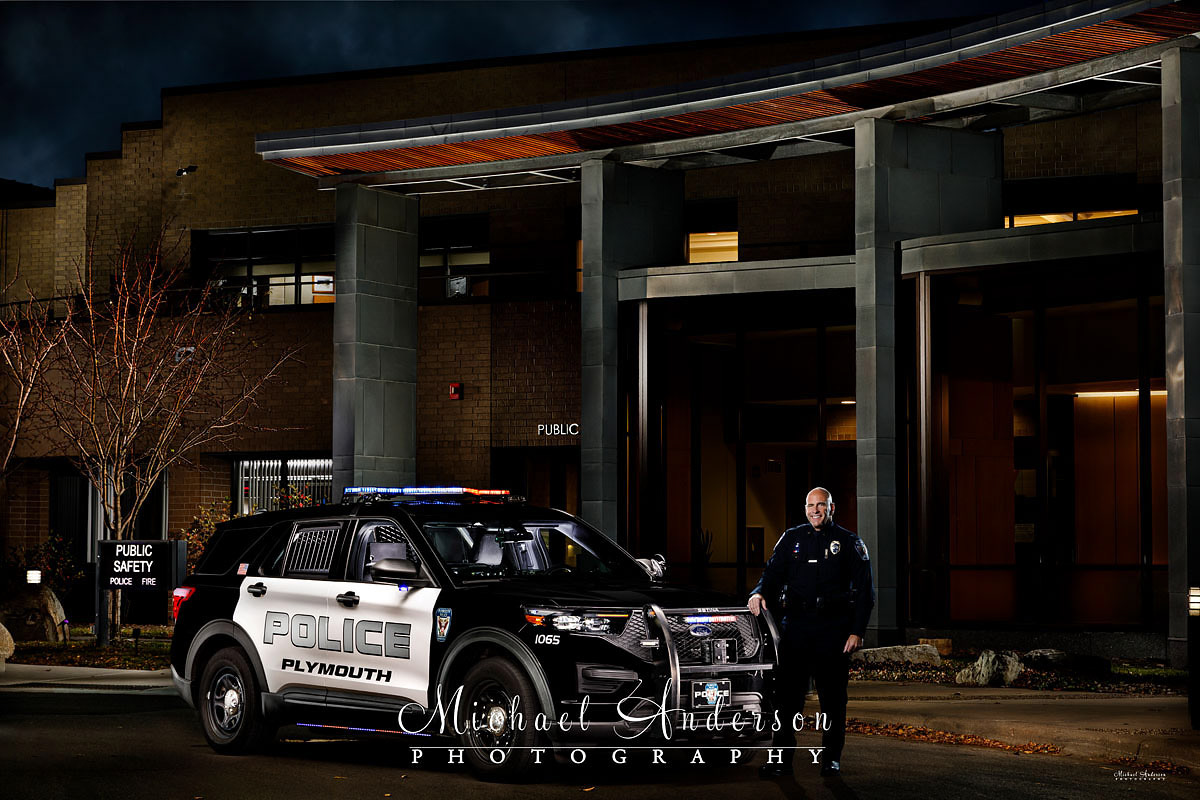 A cool light pained photograph of a Plymouth Police 2020 Ford Police Interceptor Utility, and the Chief of Police, in front of the Plymouth, MN City Hall.