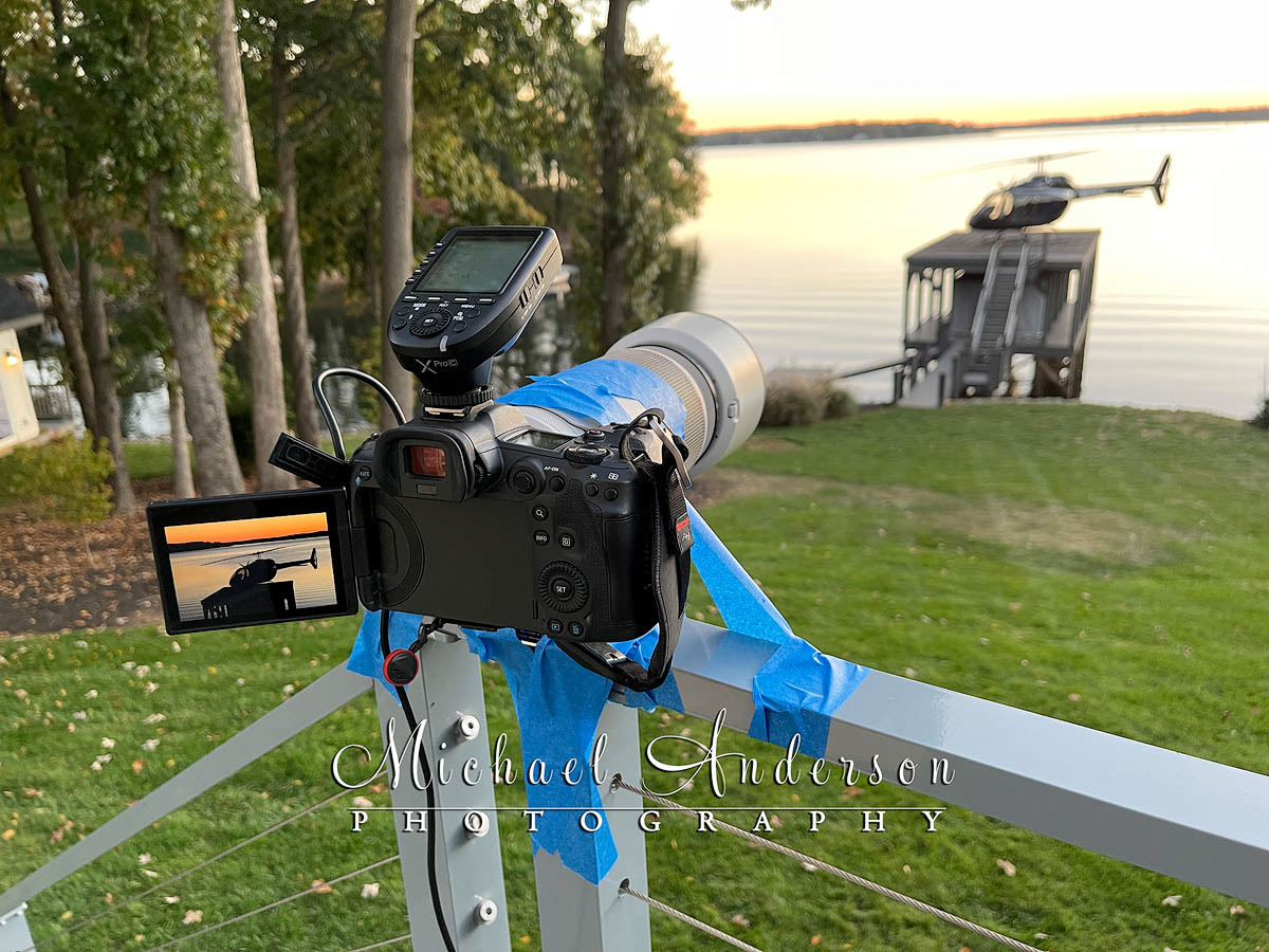 The setup photo for the light painting of a Bell 505 Helicopter at Lake Norman in North Carolina. For this image, an improvised tripod was created using a deck railing, the tripod foot on the lens, and painter's tape to hold it all in place.