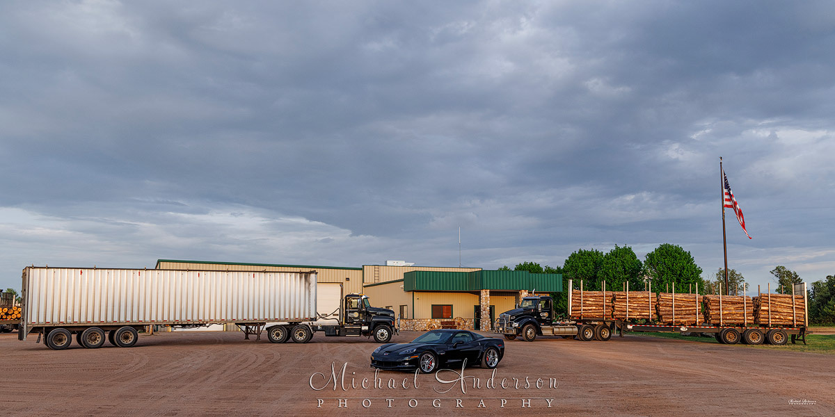 The setup photo, prior to light painting everything, of a 2023 Kenworth T880, a 2024 Mack P164T, and a 2006 Corvette Z06 in front of Fornengo Forest Products Headquarters in Danbury, WI