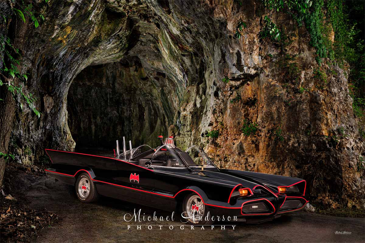 A super-cool light painted photograph of the Batmobile in front of the Batcave!