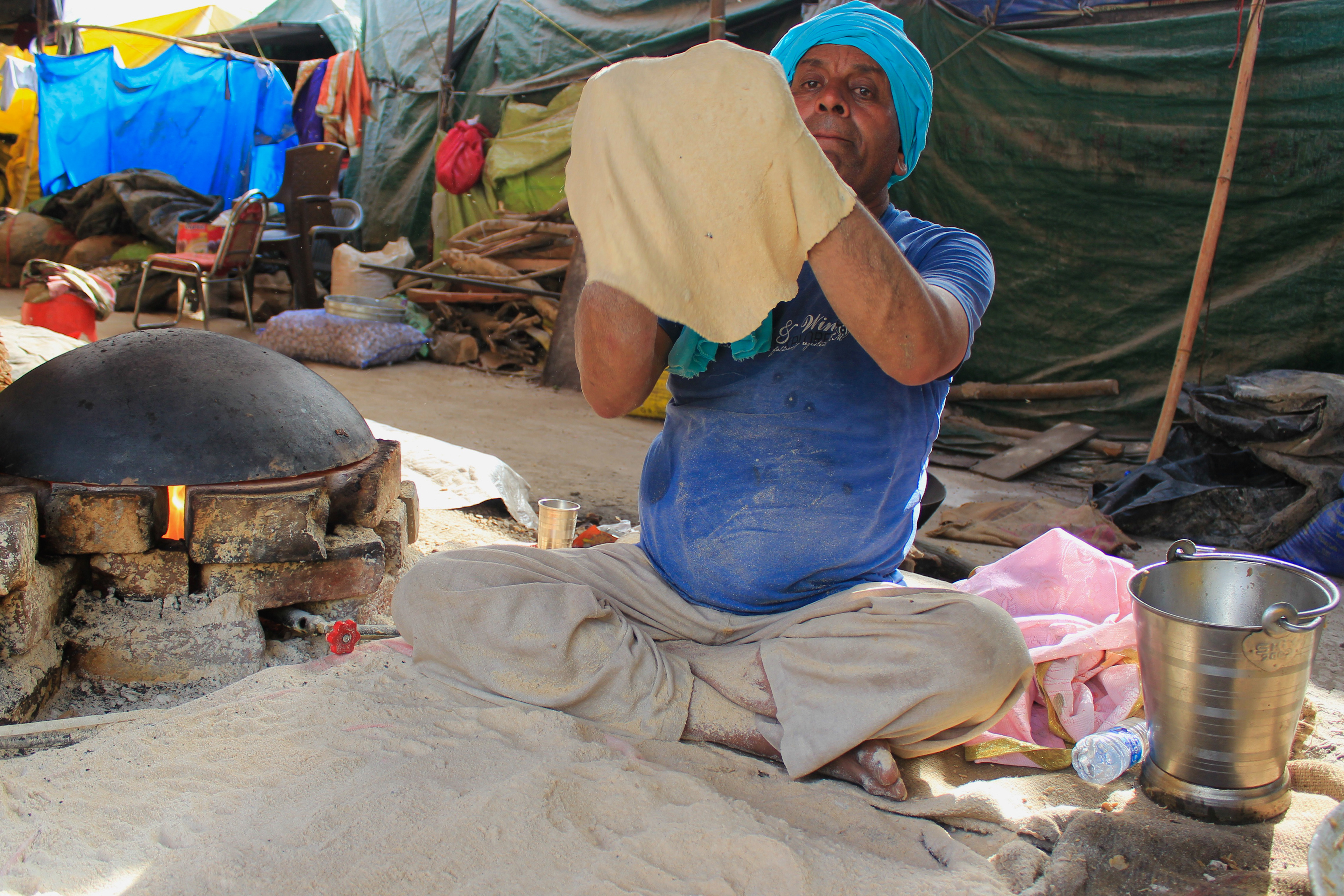 Free food is being distributed to the protesters who gather at Singhu border. Meethi Ram (right) makes hundreds of flatbreads to feed the protesters at the site.