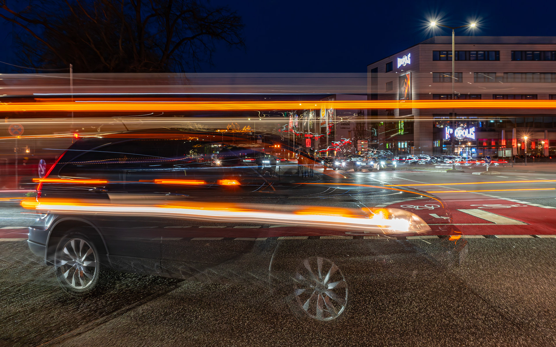 Langzeitaufnahme am Berliner Platz in Gießen mit einem halb transparenten Auto, dessen Blinker den Scheinwerfer akzentuiert