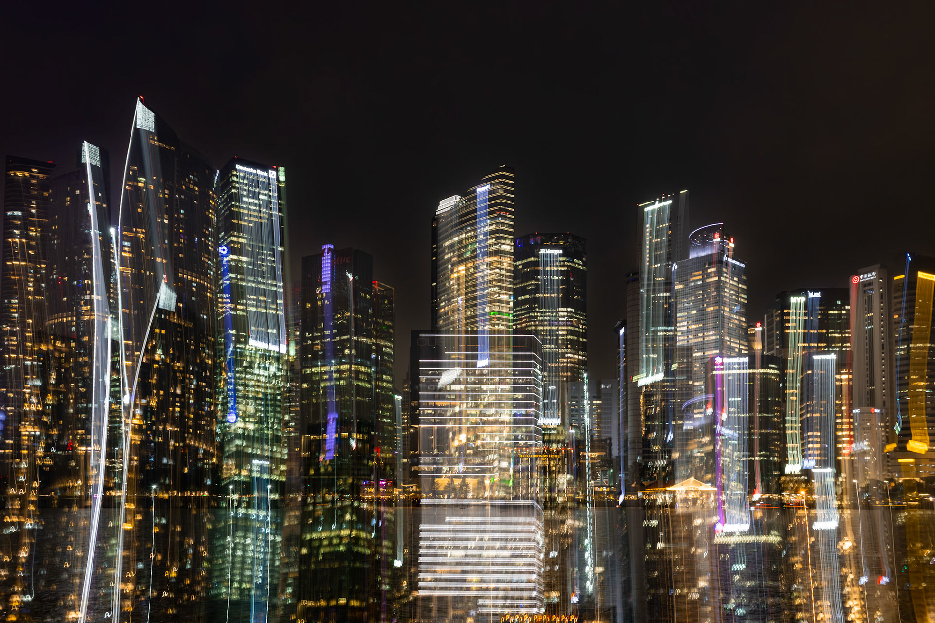 Skyline mit Bewegungsunschärfe und Lichteffekten; vertikale Strukturen wirken durch Überlagerung verzerrt.