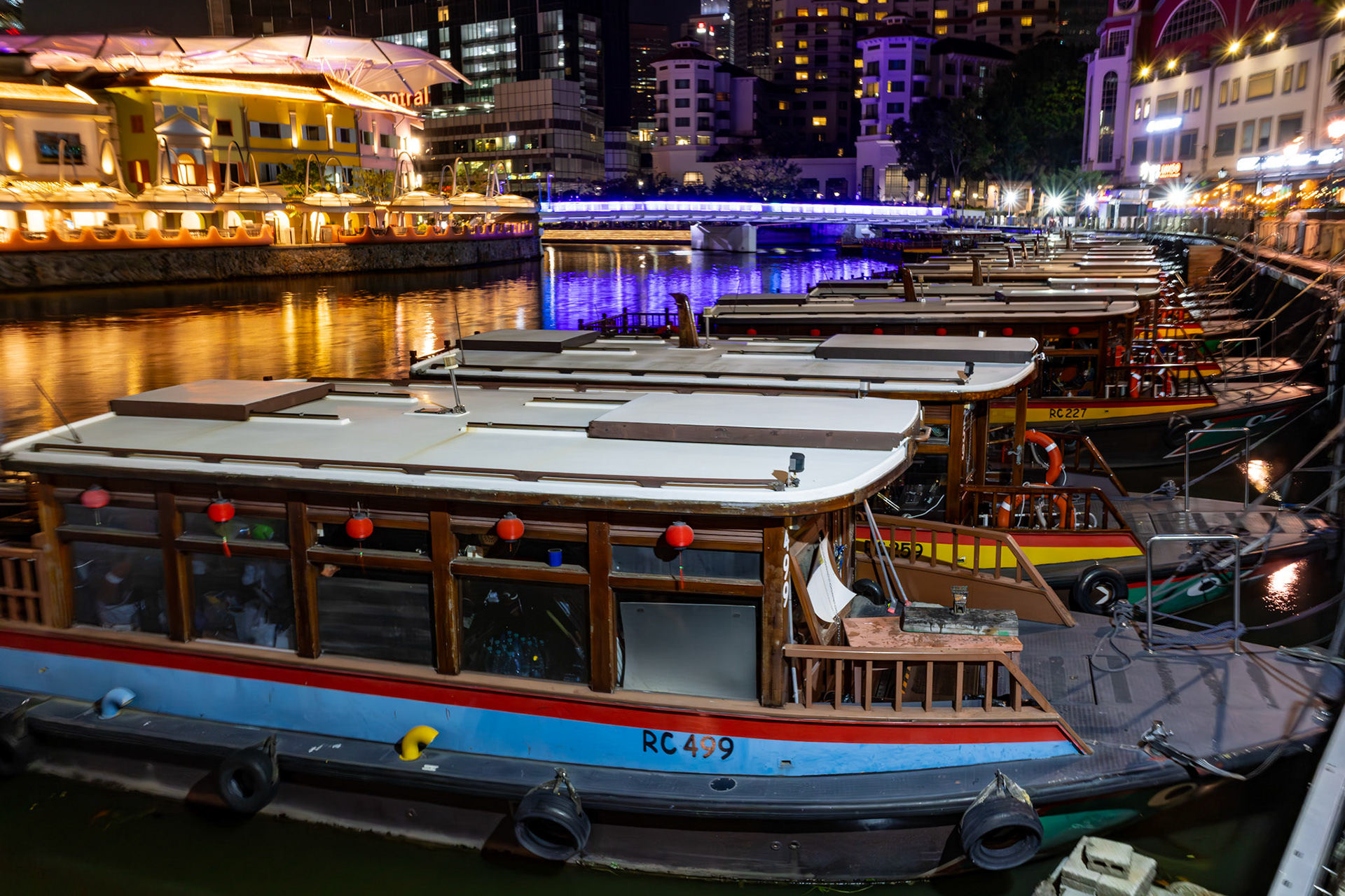 Restaurants und Boote entlang des Singapore River; dicht gereihte Lokale direkt am Wasser.