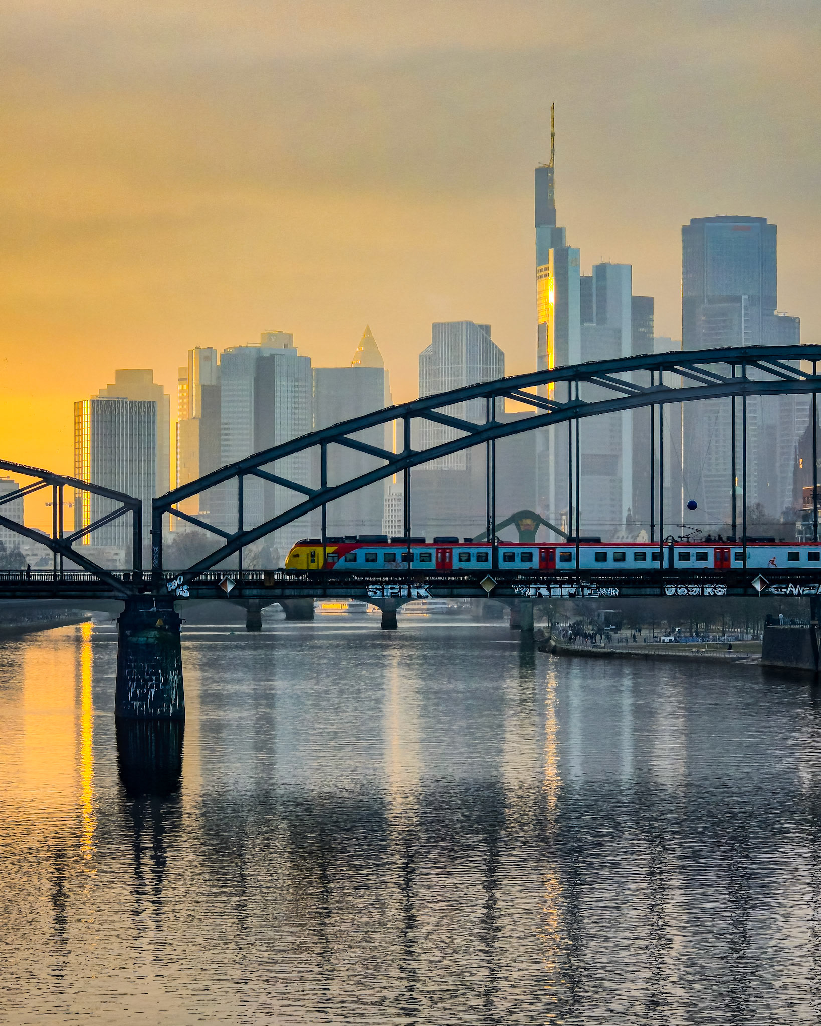 Frankfurter Skyline und Deutschherrnbrücke mit Bahn während des Sonnenuntergangs