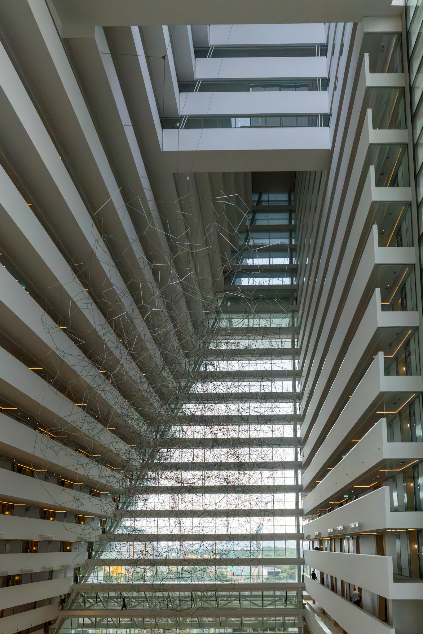Symmetrische Linien und Blick durch das Hotelinnere; wiederholende Balkone ziehen sich nach oben.