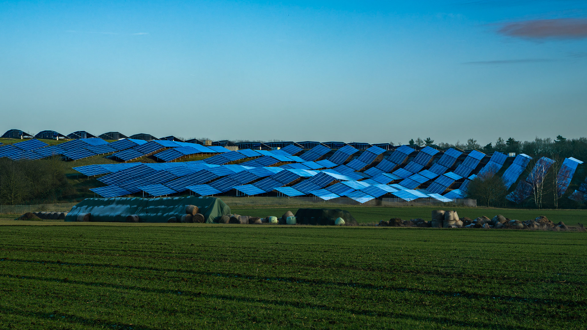 Ein Solarpark nahe Fernwald mit einem großen Acker im Vordergrund in der schwachen Wintersonne
