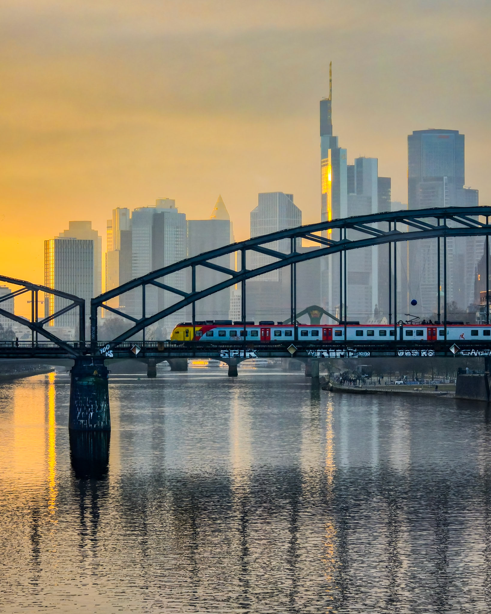 Frankfurter Skyline und Deutschherrnbrücke mit Bahn während des Sonnenuntergangs