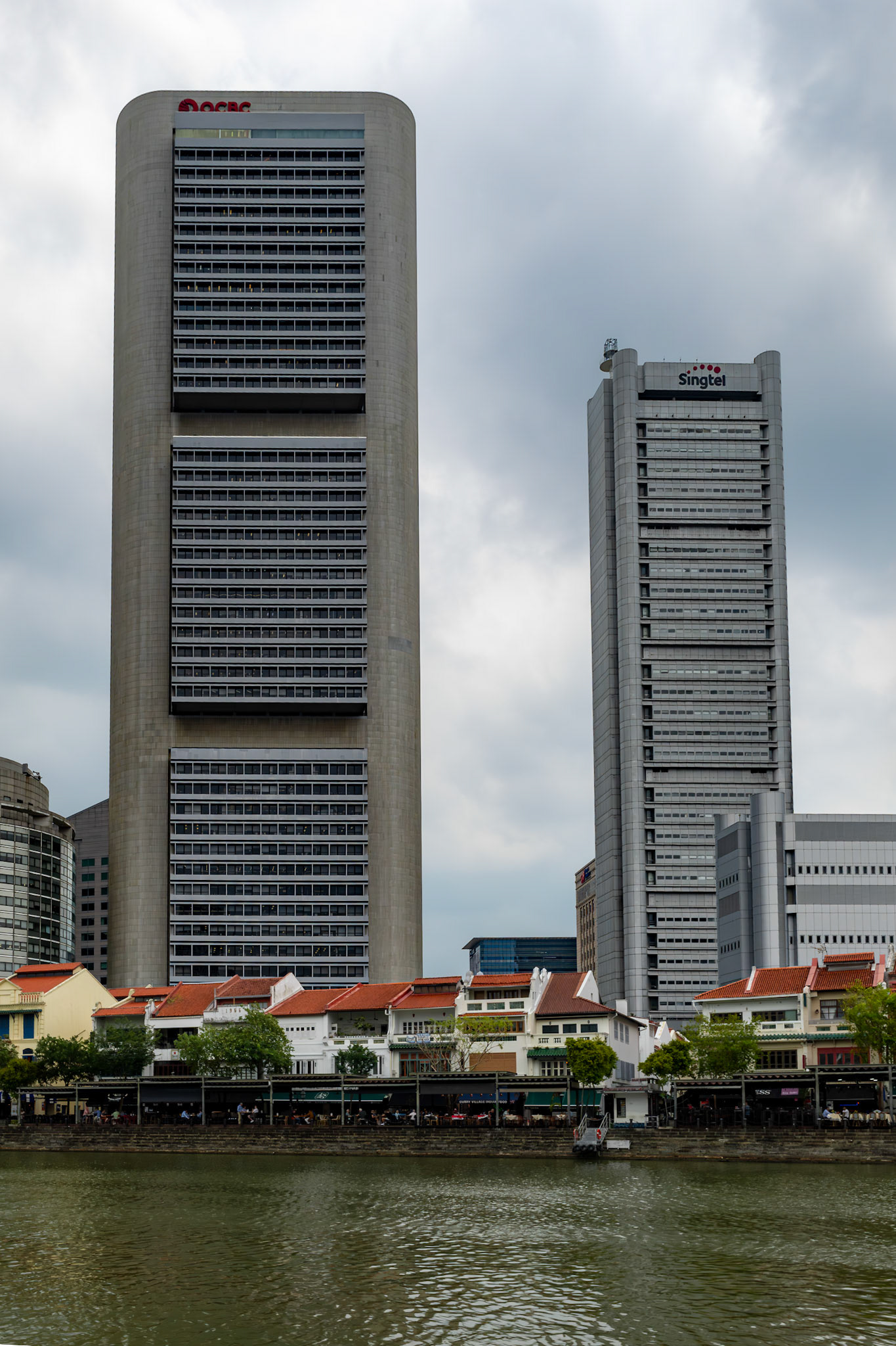OCBC Centre am Singapore River bei Tageslicht; im Vordergrund traditionelle Low-Rise-Gebäude entlang des Flussufers.