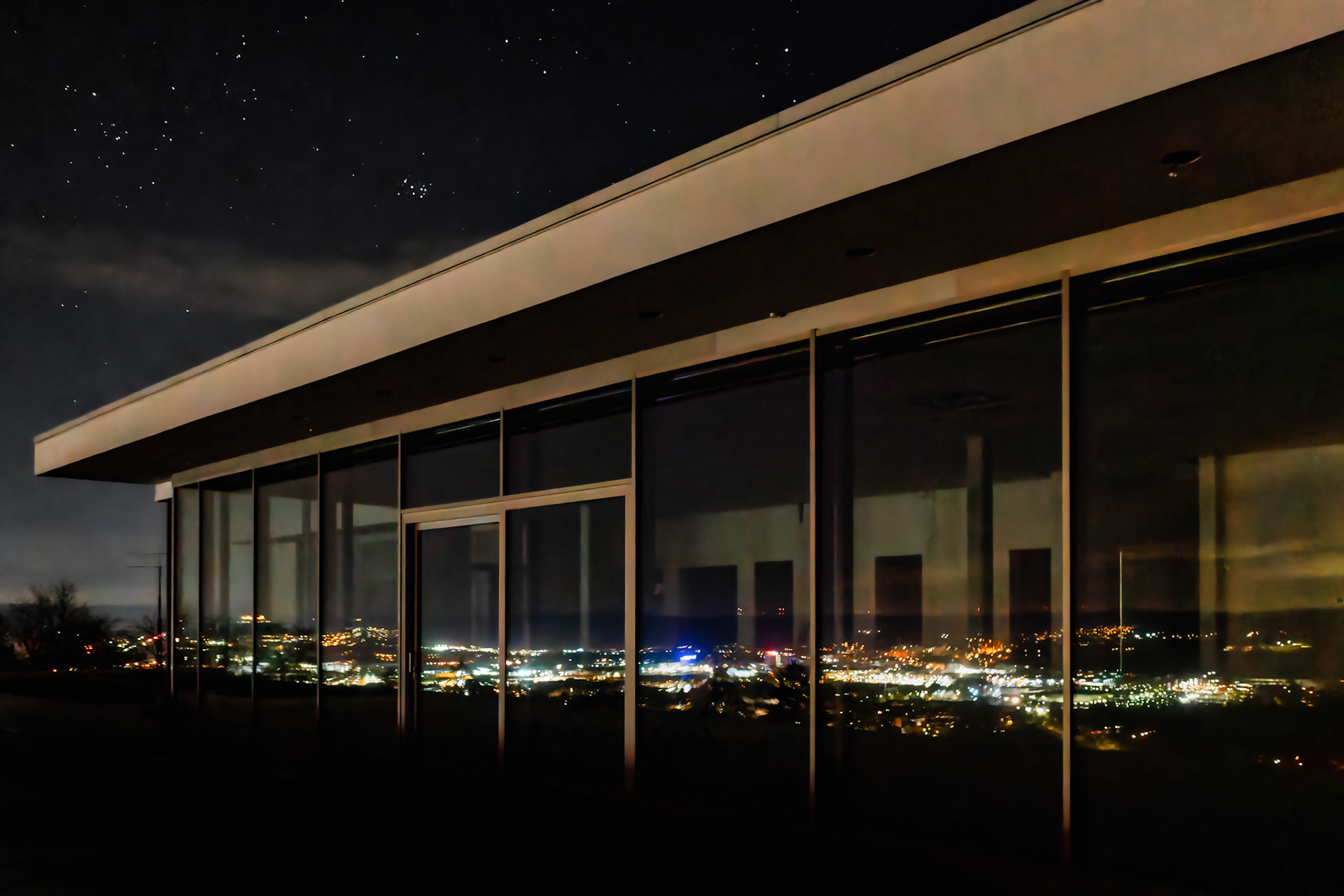A reflection of Wetzlar at night in the window of a restaurant on a hill closeby overlooking the Lahn river valley