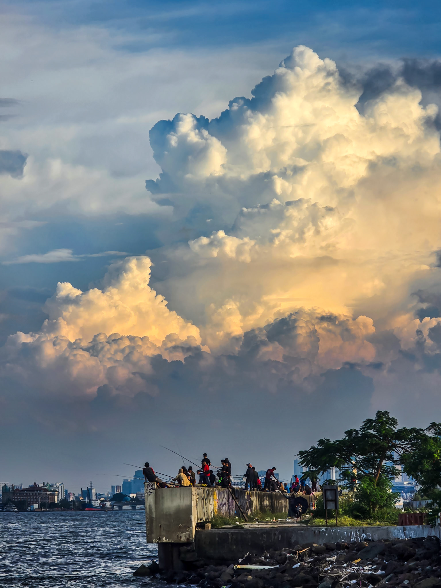 Angler unter Wolkenpracht in Jakarta, Tanggul Muara Baru, Smartphone