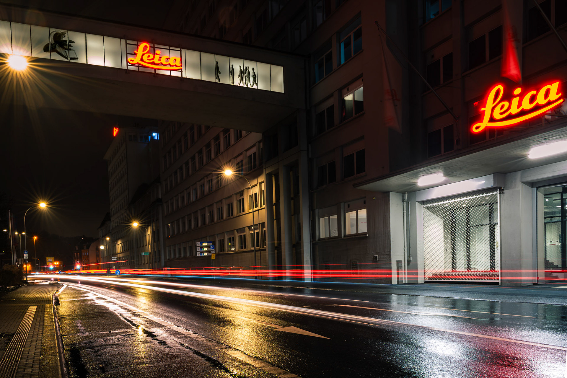 Altes Leitz-Gebäude bei Nacht mit beleuchteten Logos und Lichtspur