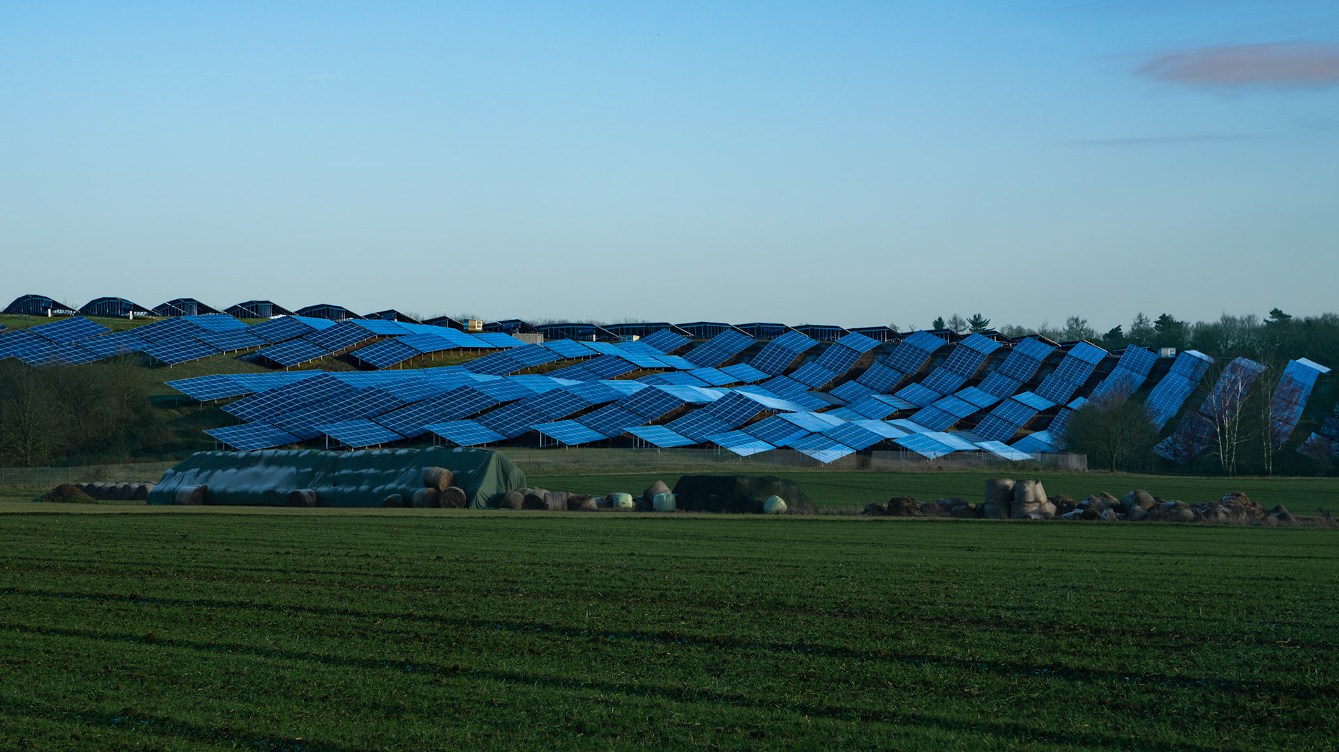 Ein Solarpark nahe Fernwald mit einem großen Acker im Vordergrund in der schwachen Wintersonne
