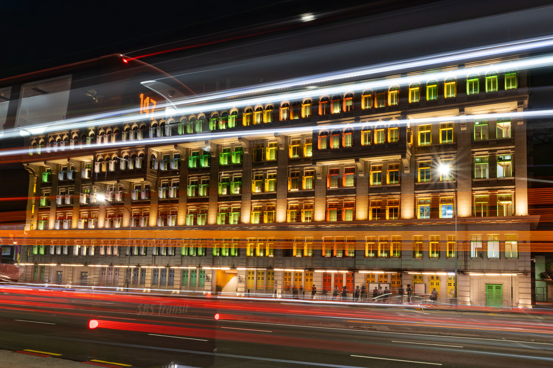 Langzeitbelichtung der beleuchteten Fassade der Old Hill Street Police Station in Singapur mit vorbeiziehendem Verkehr - prominent zu sehen: Bus 147.