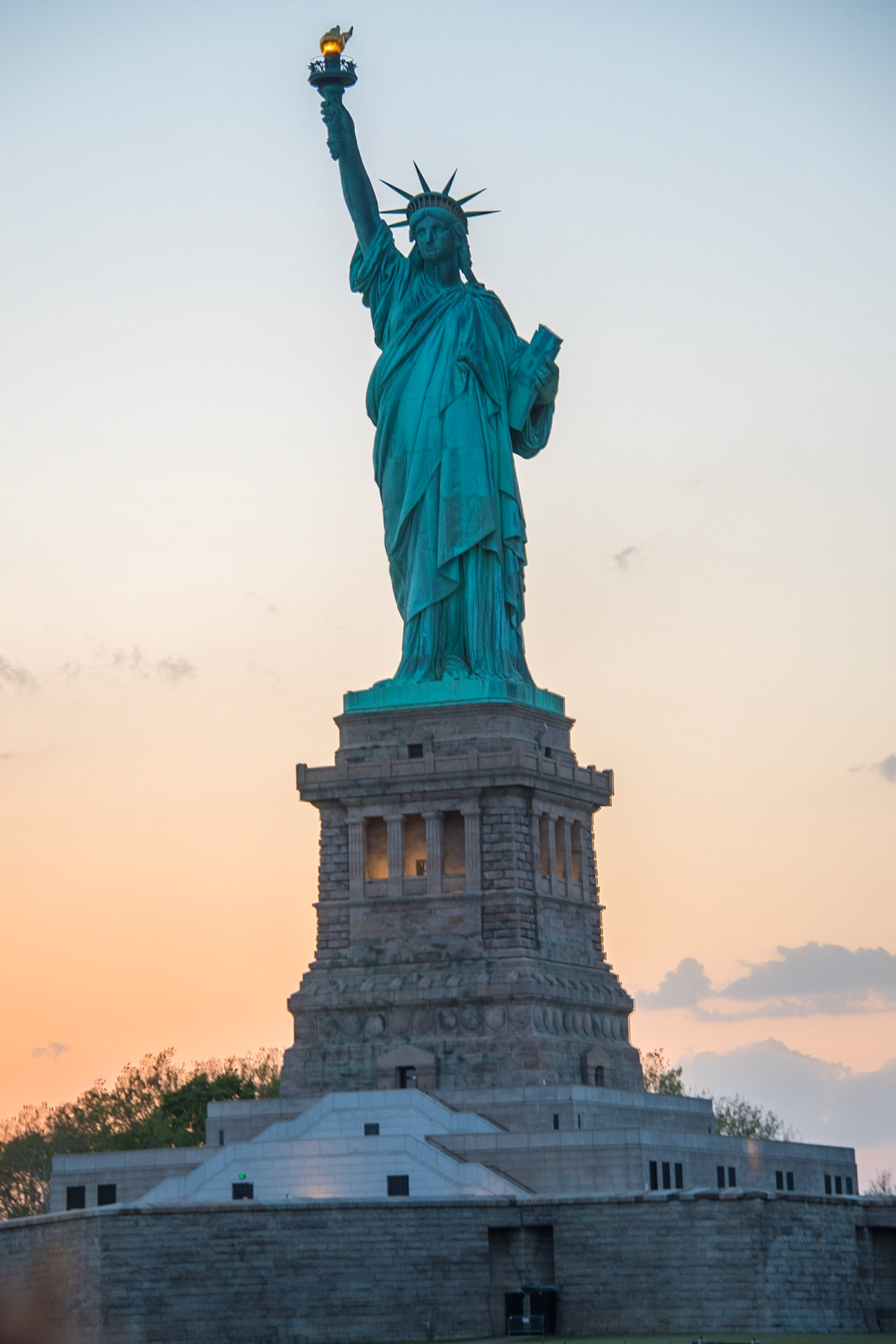 The Statue of Liberty (Liberty Enlightening the World; French: La Liberté éclairant le monde) is a colossal neoclassical sculpture on Liberty Island in New York Harbor in New York City, in the United States. The copper statue, designed by Frédéric Auguste Bartholdi, a French sculptor and dedicated on October 28, 1886, was a gift to the United States from the people of France. The statue is of a robed female figure representing Libertas, the Roman goddess, who bears a torch and a tabula ansata (a tablet evoking the law) upon which is inscribed the date of the American Declaration of Independence, July 4, 1776. A broken chain lies at her feet. The statue is an icon of freedom and of the United States: a welcoming signal to immigrants arriving from abroad.