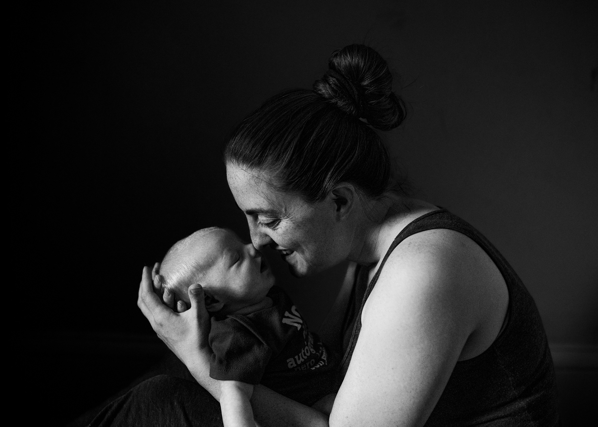 A mom holding her new baby, with noses touching. In black and white