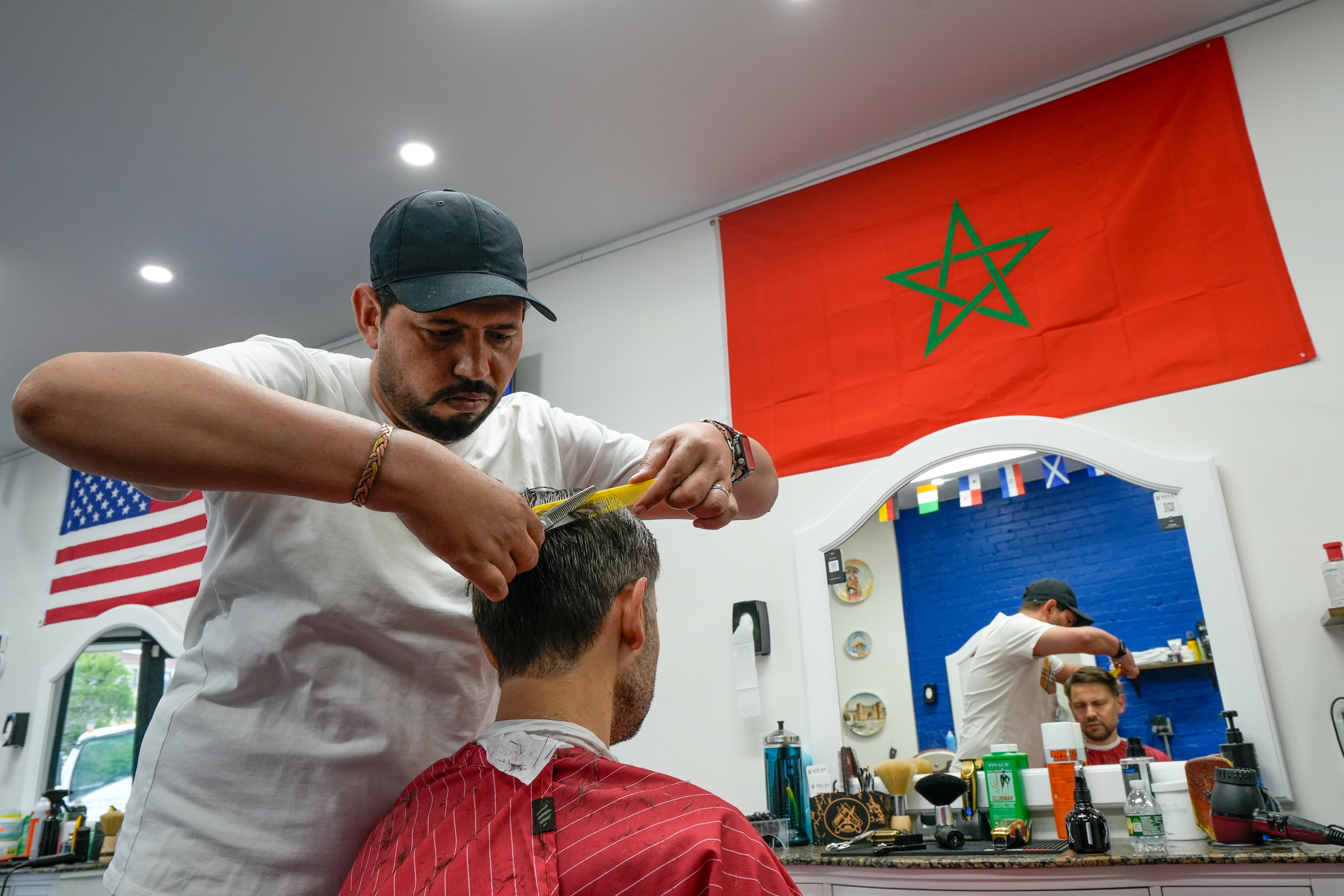 Barber Salah Abouelouafa tends to a customer on June 23, 2026 at Atlas Barbershop in Brookline, Mass. Atlas Barbershop held World Cup watch parties for both U.S. and Moroccan matches, and attendees would bring traditional Moroccan dishes for viewers to share.