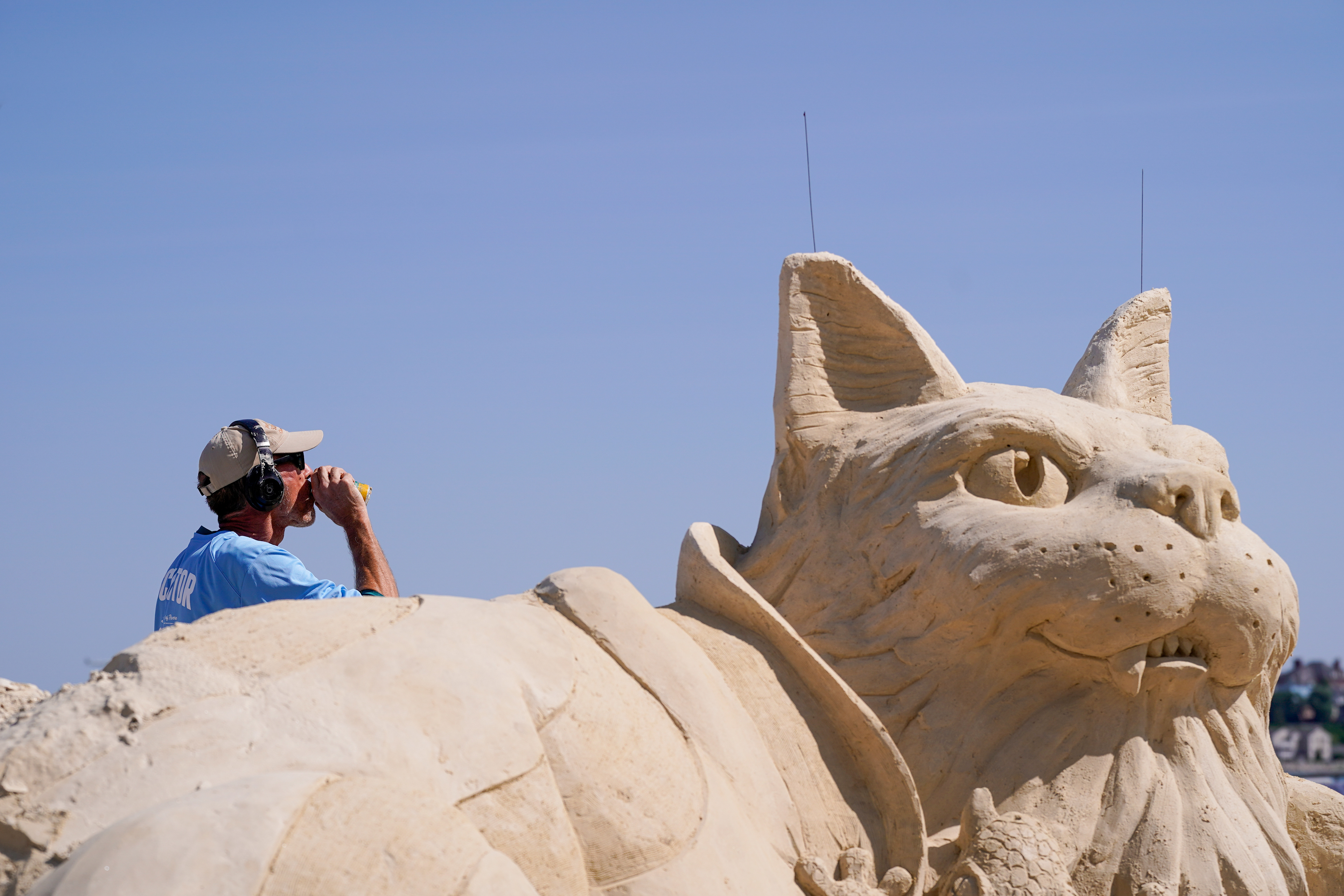 Florida sand sculptor Patrick Harsch takes a hydration break while working on his sculpture during the Revere Beach International Sand Sculpting Festival on July 17, 2026 in Revere, Mass.
