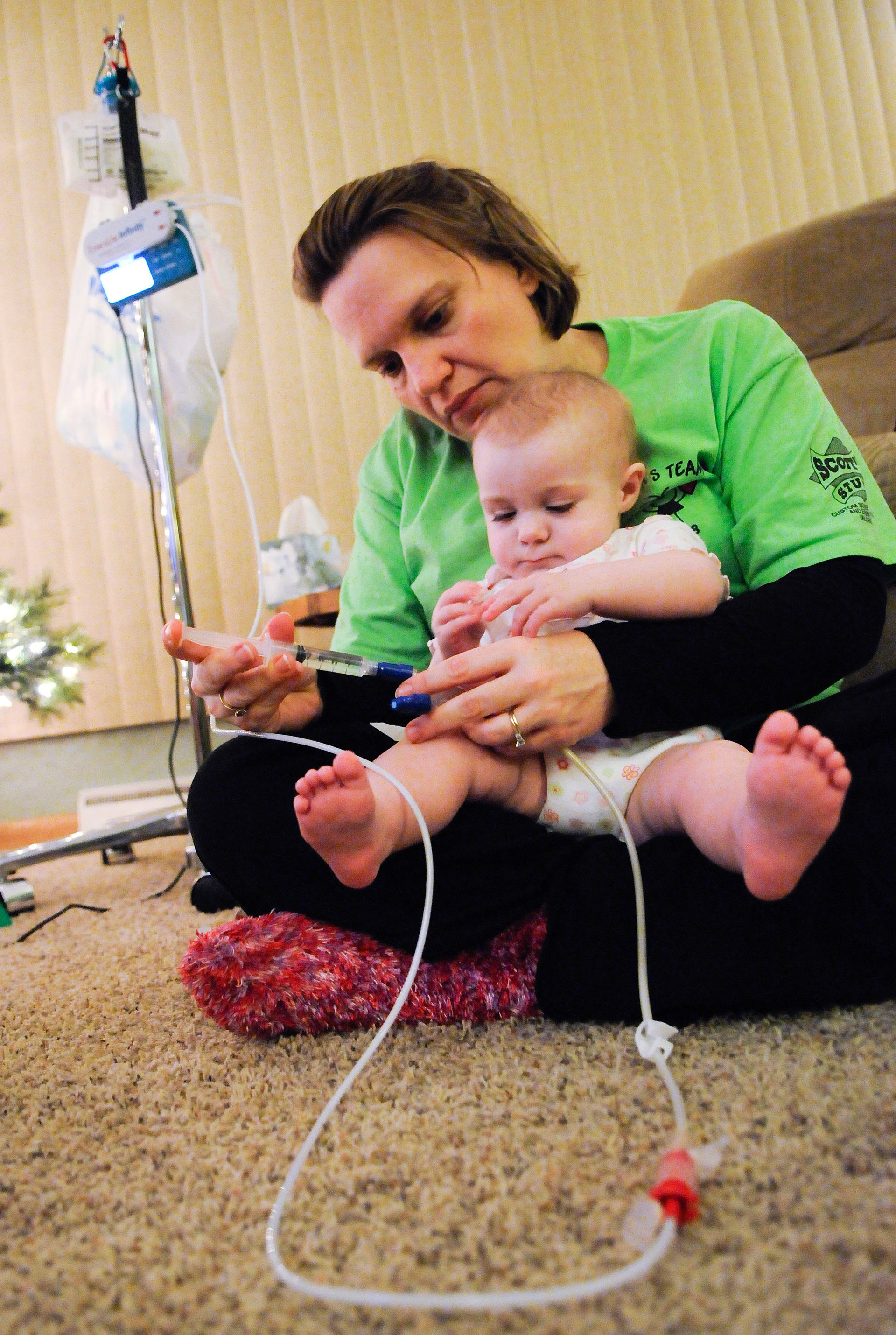 Missy Leonardson of Whitelaw administers 5 milliliters of vancomycin-heparin flush via the central line to her 16-month-old daughter, Dani, on a recent night in the living room of their Whitelaw home. For a couple of weeks, the procedure was done each night as part of antibiotic treatments to fight off an infection that developed in the central line. Dani, who feeds 20 hours each day via a gastrostomy tube that is attached to the apparatus in the background, has an undiagnosed medical condition. Doug Sundin/HTR December 9, 2008