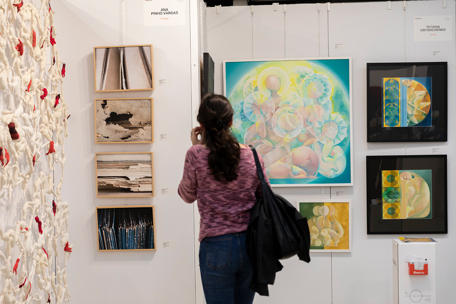 A visitor observing Tetiana Gryshchenko’s geometric–figurative artworks at Florence Biennale 2025, including the large circular composition and smaller pieces from the series.