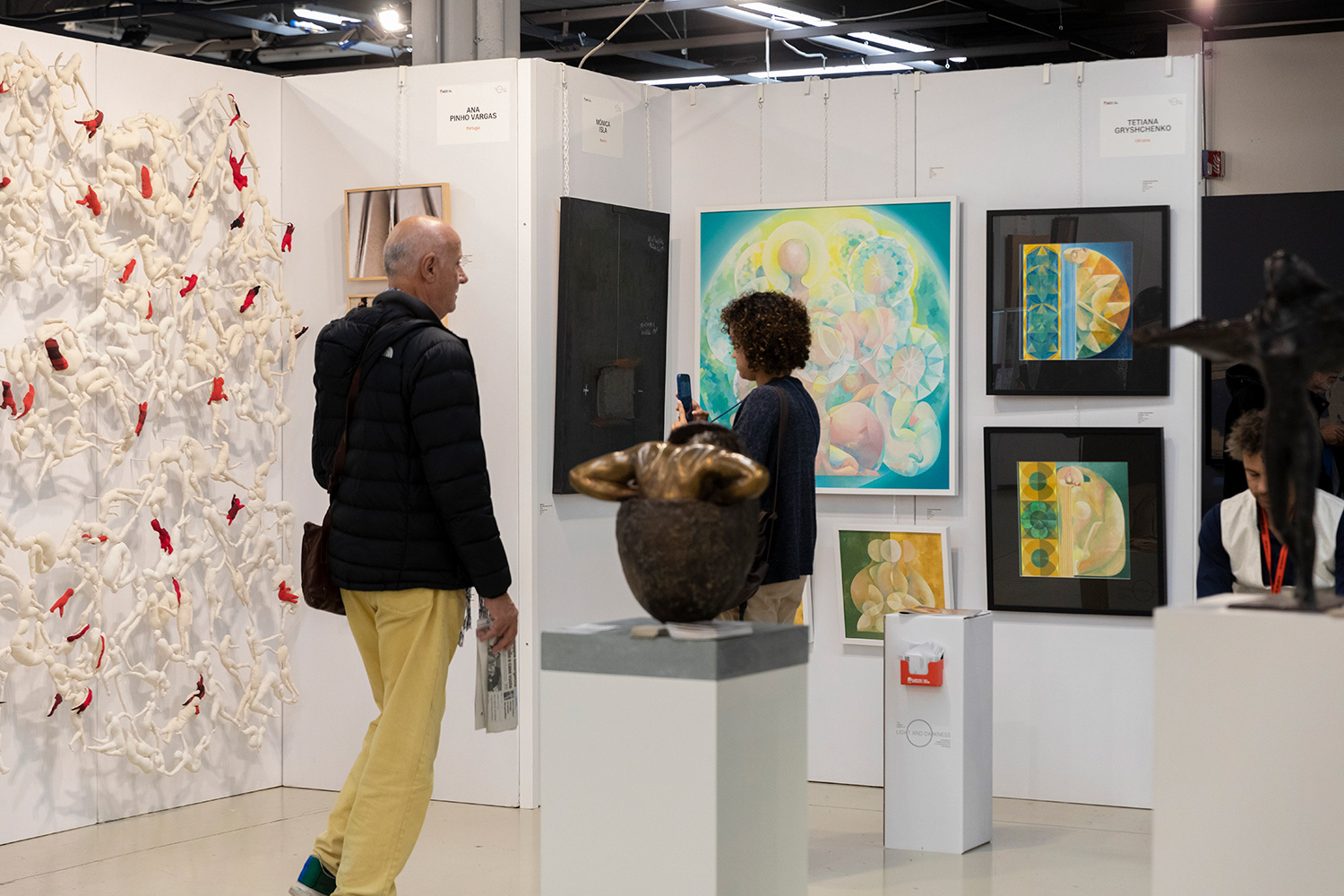 Visitors exploring Tetiana Gryshchenko’s exhibition space at Florence Biennale 2025, viewing her geometric paintings and abstract figurative compositions.