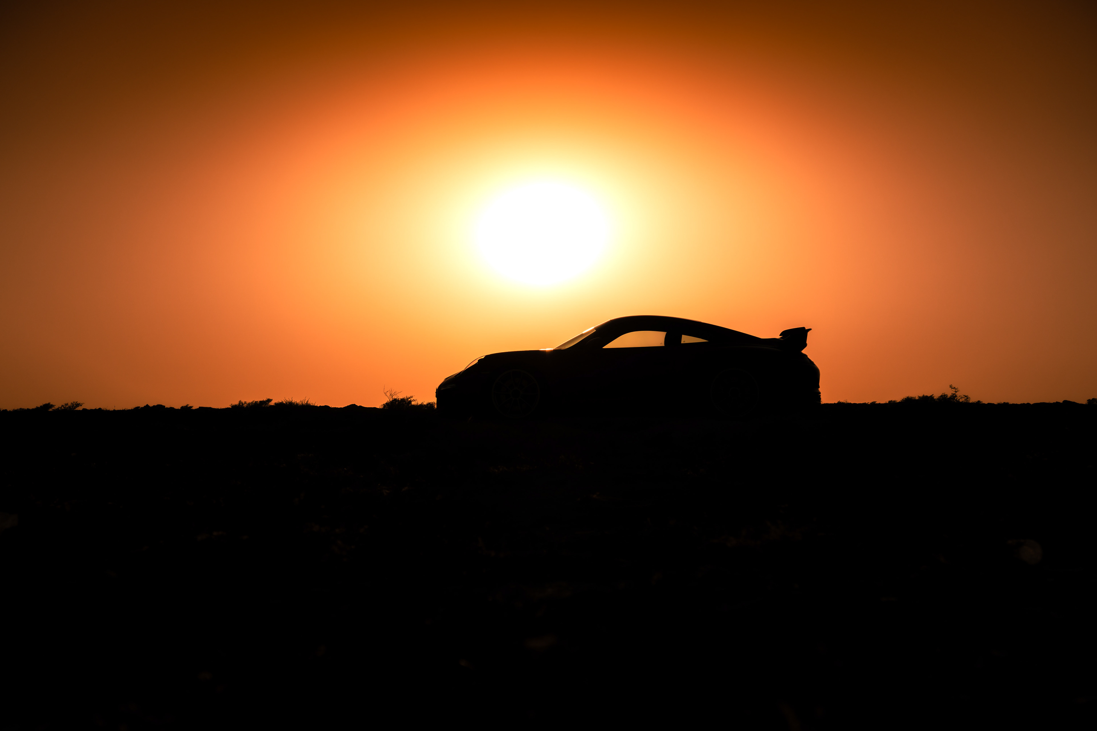 Side profile of the GT3 cutting through desert sands under warm light.