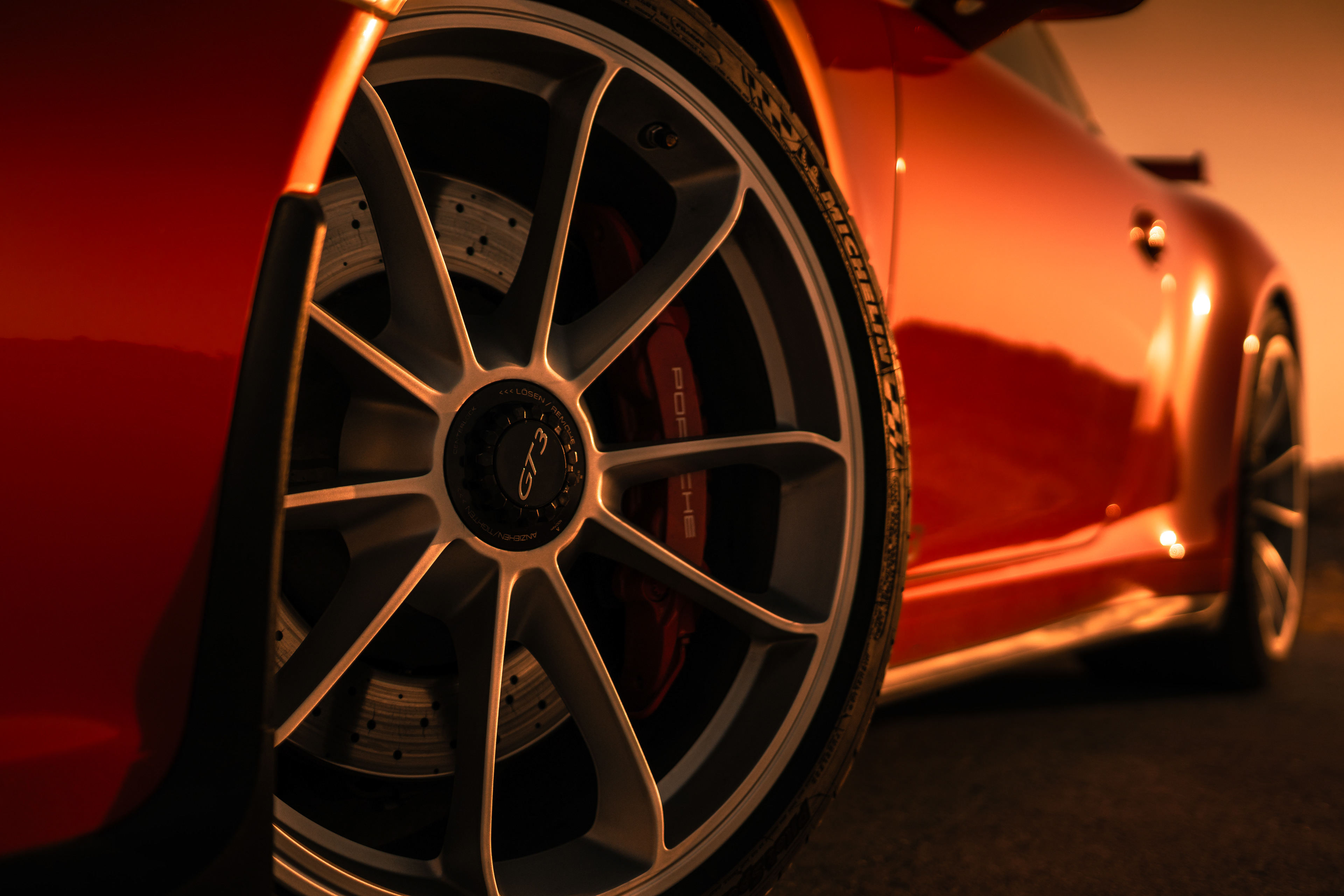 Close‑up of forged porsche GT3 wheel and red brake caliper with drilled carbon‑ceramic disc.