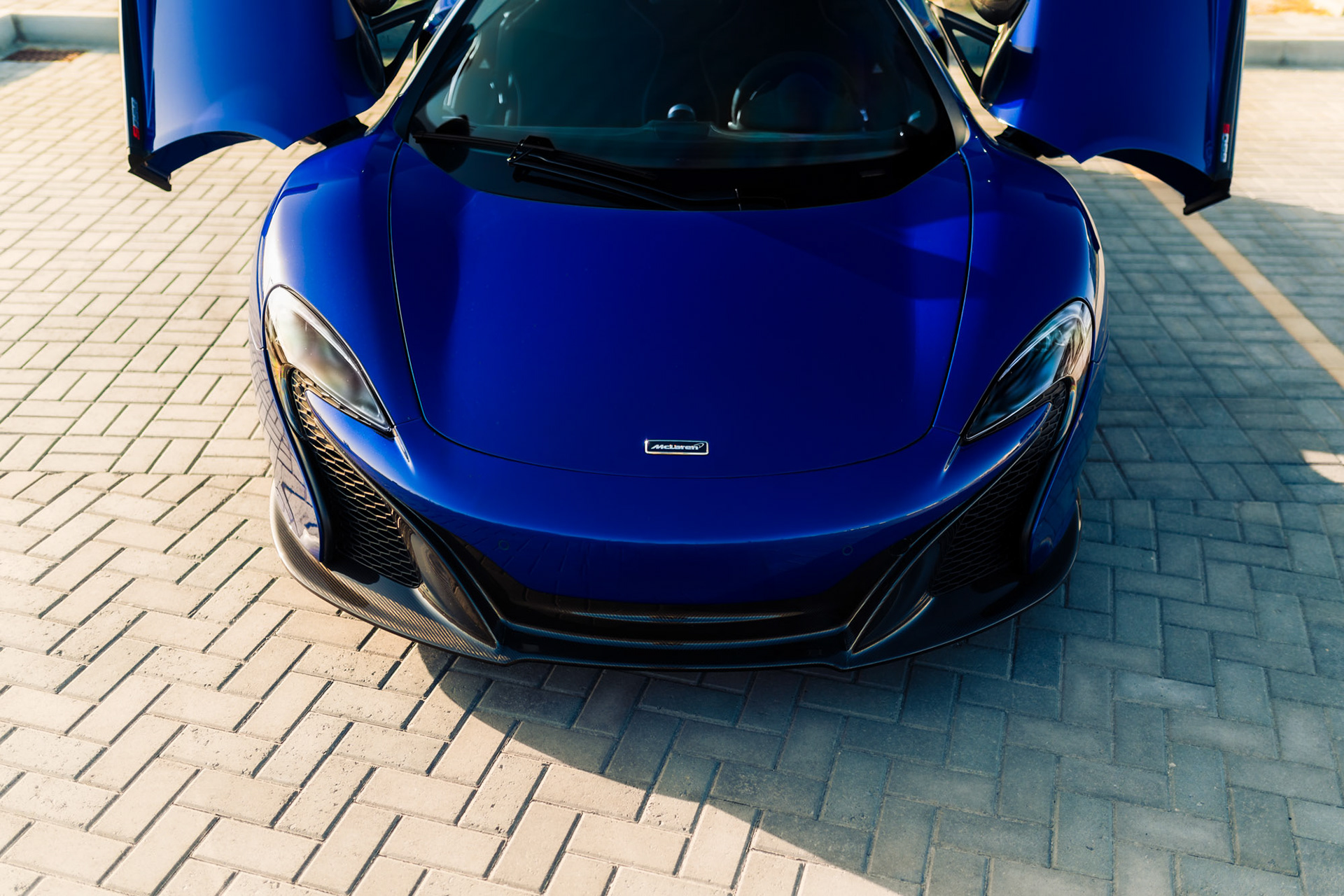 Top-down front view of the McLaren 650S Spider in Bahrain with doors open, showing the sculpted hood and aerodynamic design in bright daylight