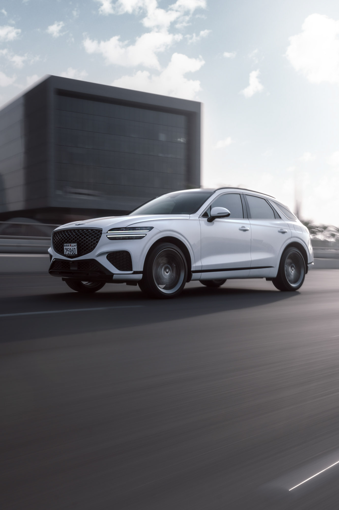 Genesis GV70 rolling shot across Manama with Bahrain skyline and World Trade Center in the background