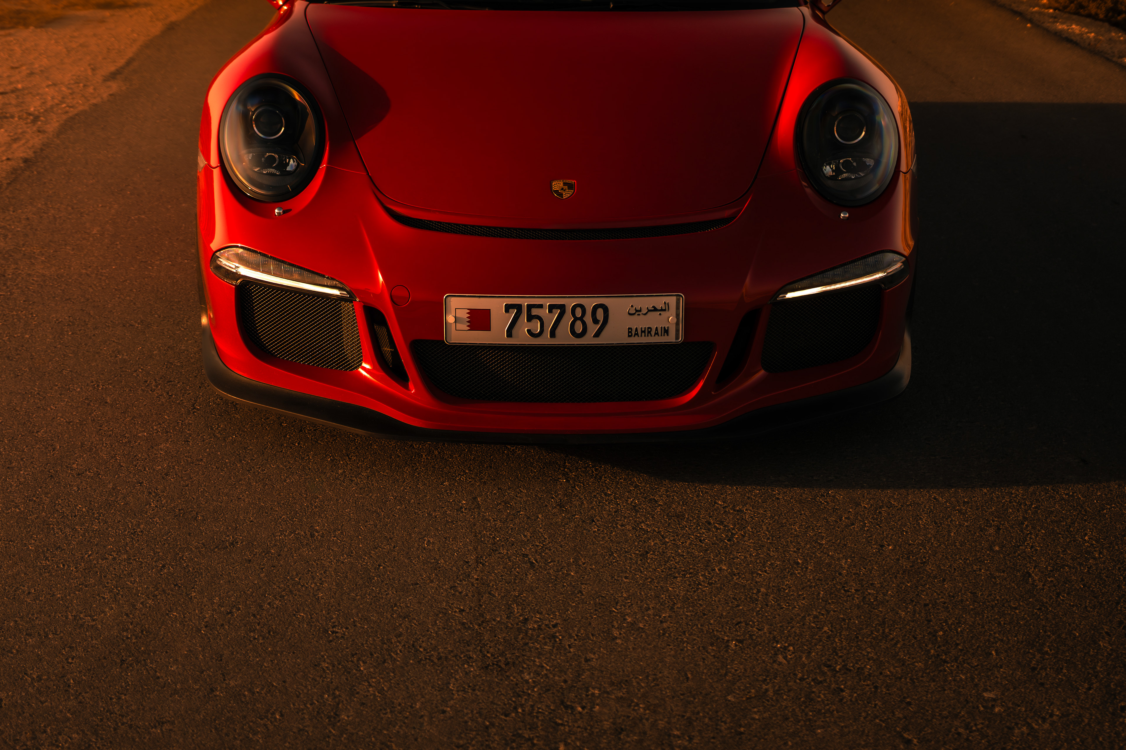 Close‑up of Porsche 911 GT3 nose at dusk showing headlights, bumper and Bahrain number plate.