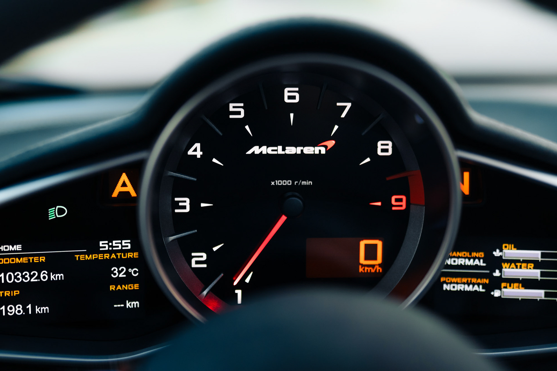 Close-up of the McLaren 650S Spider tachometer showing the McLaren logo and redline at 8500 rpm inside the cockpit.