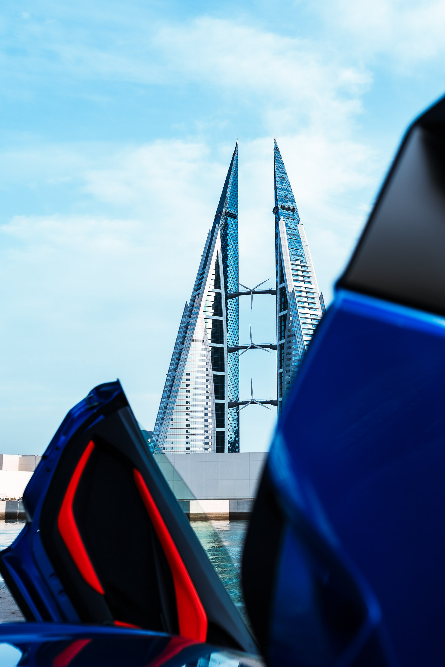 Blue Lamborghini Revuelto with scissor doors open, shot in front of Bahrain Bay towers in Manama
