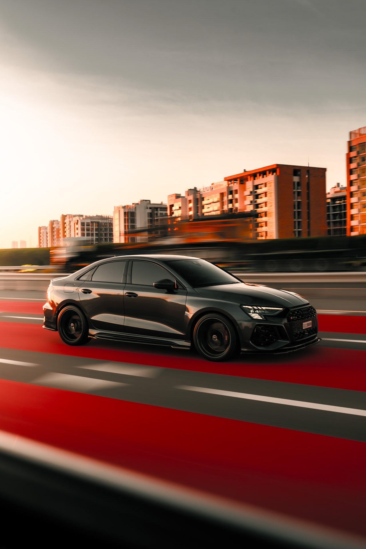 Audi RS3 driving at speed through Dubai city road with motion blur and sunset light